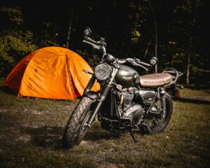 moto nue brune garée à côté d'une tente de camping orange